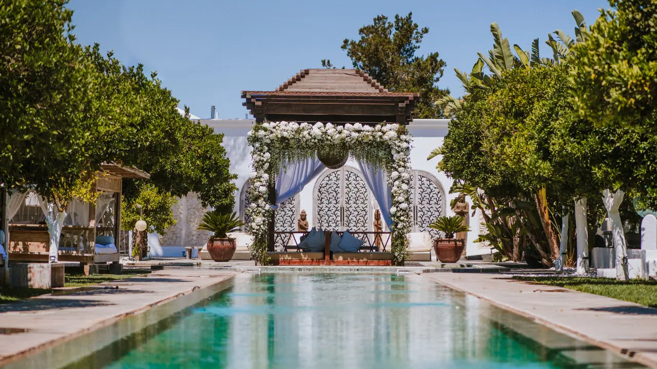 Long reflecting pool leading to a gazebo draped in white flowers at an Ibiza venue