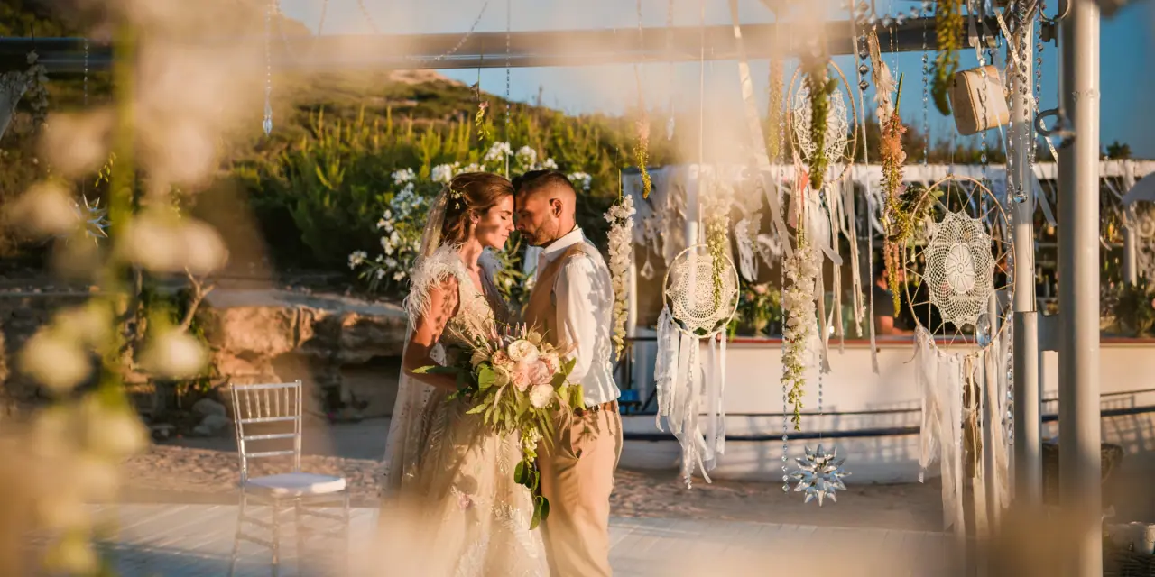 Kenton and Hassiba seen through soft-focus flowers at their dreamcatcher ceremony, Codolar, Salinas