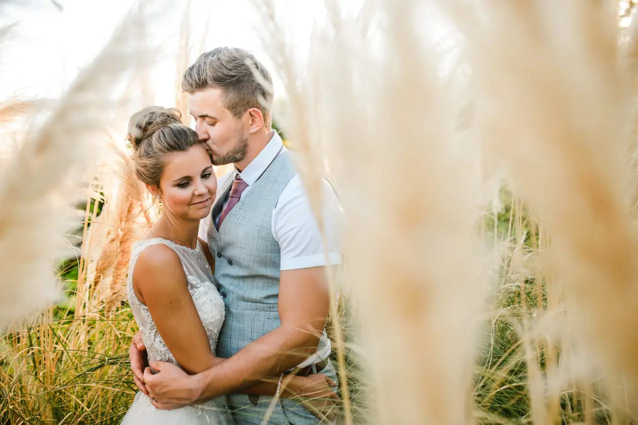 Naomi and Dale embracing among pampas grass in golden light at Nissi Beach Resort, Ayia Napa