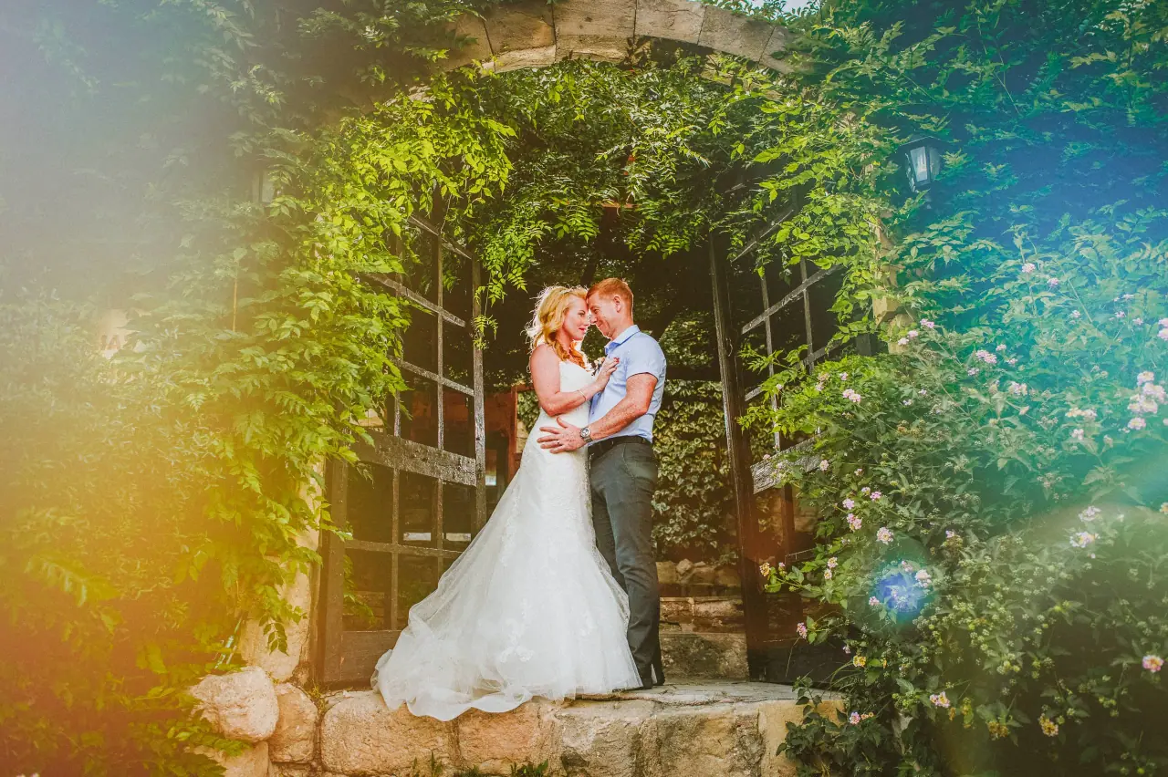 Siobhan and Mark embracing under the ivy-covered stone archway at Vasilias Nikoklis Inn, Paphos