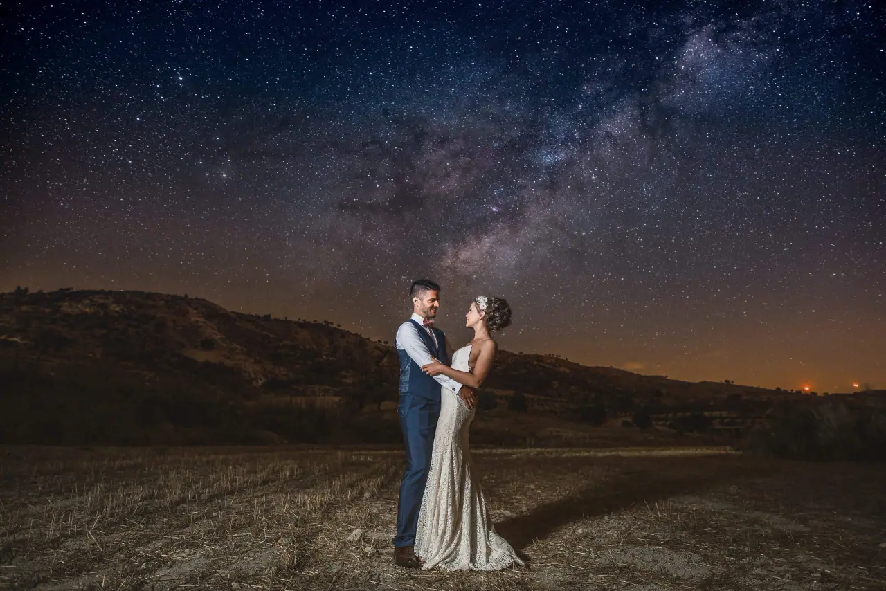 Alex and Anthony embracing under a starry Milky Way sky in the hills near Vasilias Nikoklis Inn