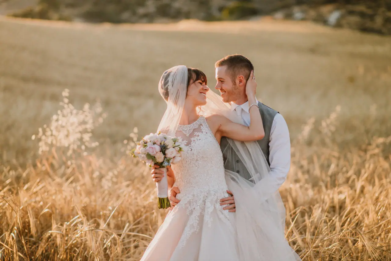 Bride with her bouquet holding the groom's face in a golden wheat field near Vasilias Inn, Kouklia
