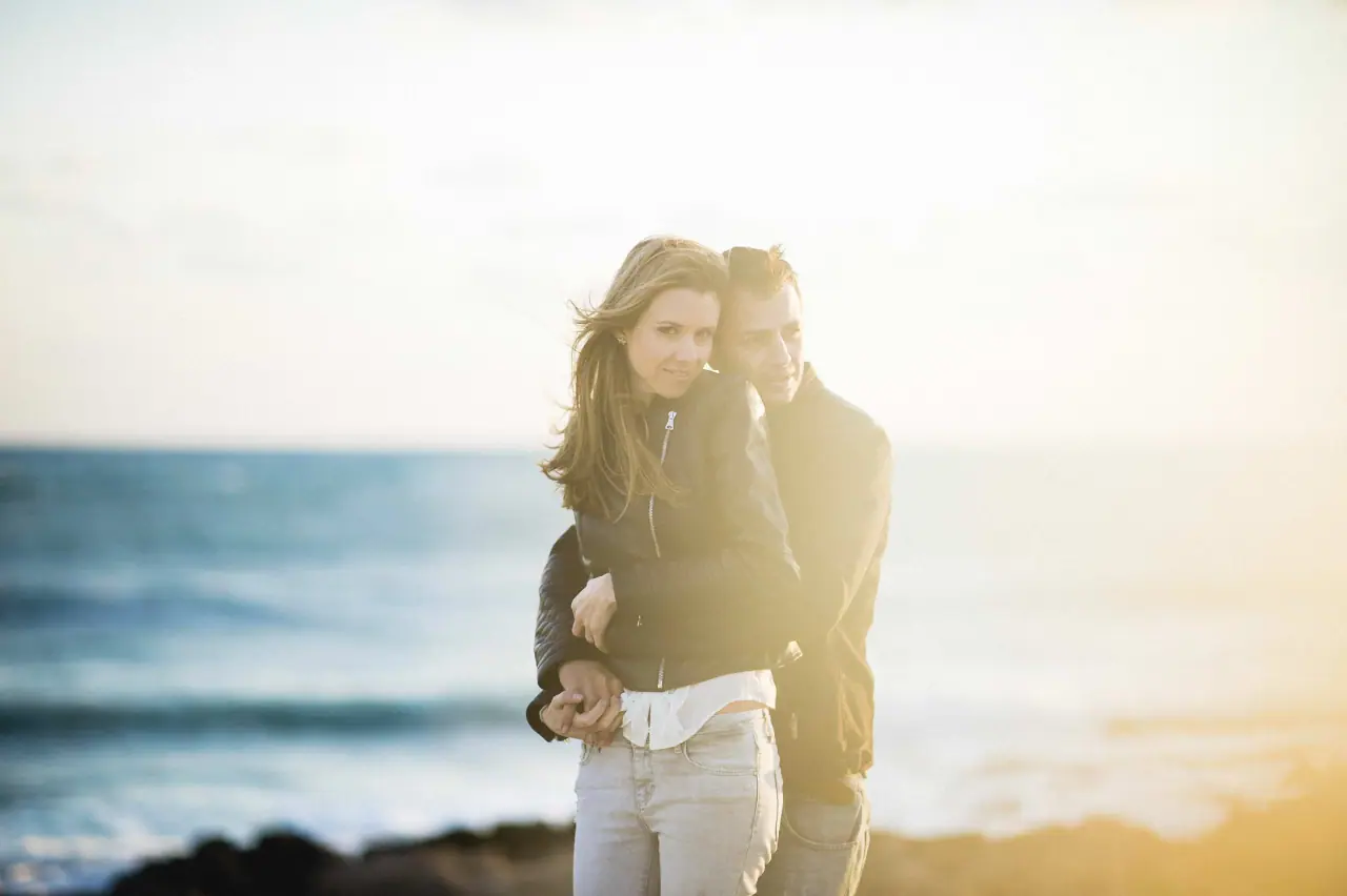 Joanna and Andrew embracing on the shore in hazy golden light, Paphos