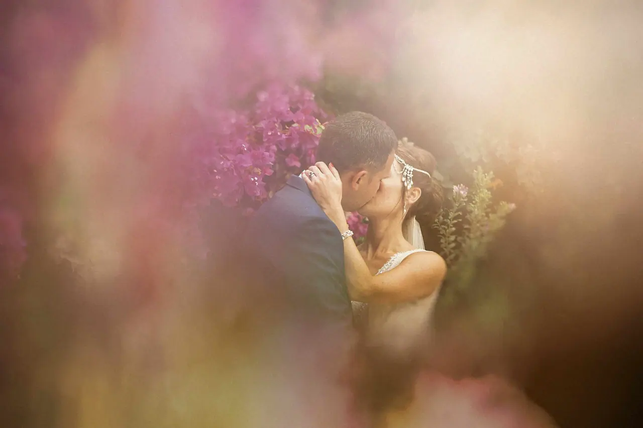 Donna and Byron kissing behind a soft blur of pink bougainvillea at Vasilias Nikoklis Inn, Paphos