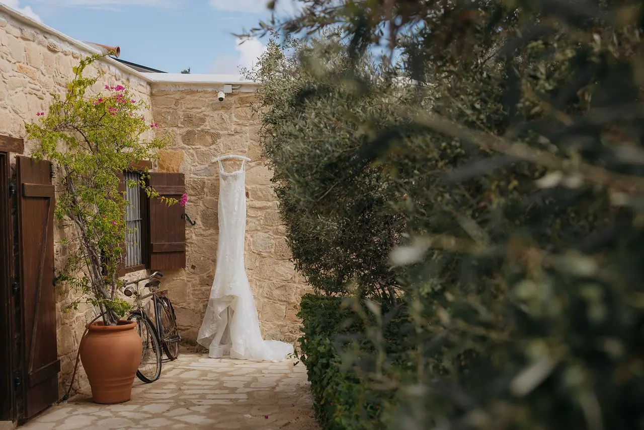 Zoe's wedding dress hanging in a stone courtyard at Liopetro beside a vintage bicycle