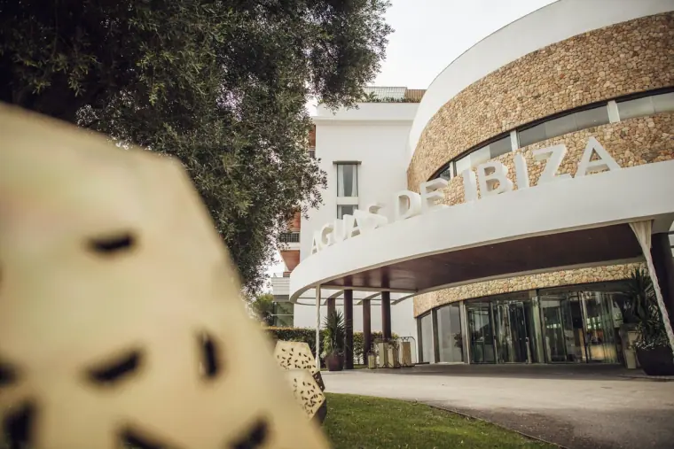 Curved white hotel facade with its Ibiza sign, framed by a blurred lampshade