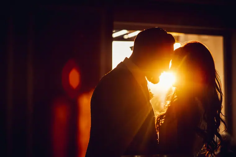 Couple silhouetted kissing in a doorway as the sun bursts between them at Anassa Hotel