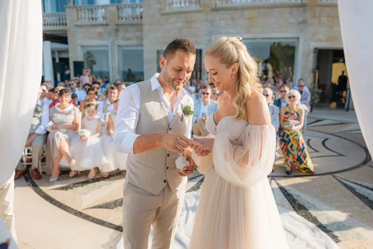 Peter placing the ring on Jade's finger as guests watch the terrace ceremony
