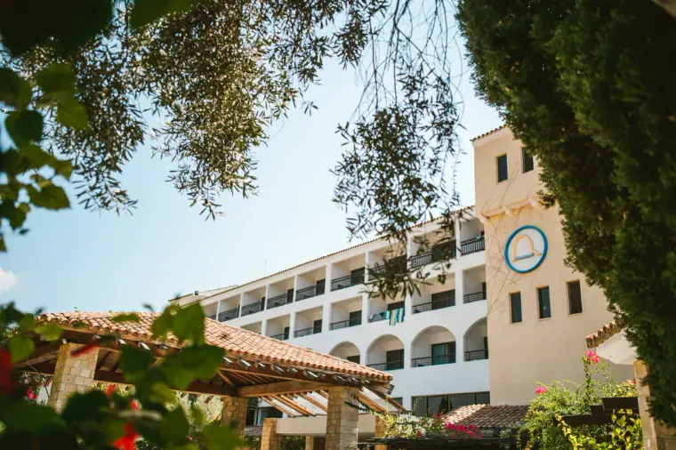 Coral Beach Hotel, Paphos, framed by olive branches under a clear blue sky