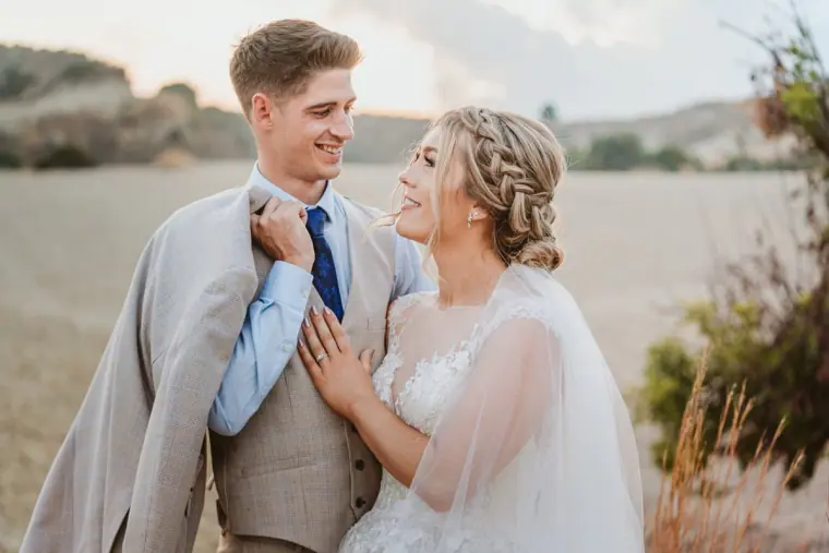 Groom in a beige suit laughing with the bride in the dry Cypriot countryside