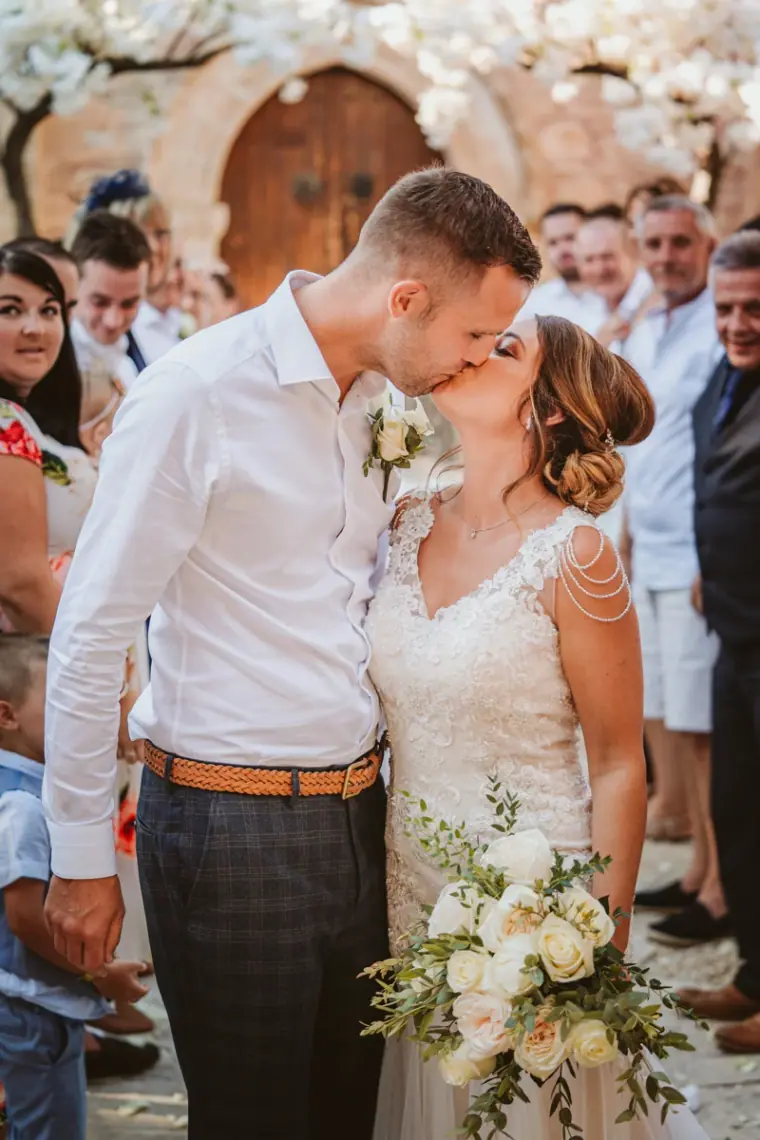 Ellie and Jack kissing as guests cheer after the ceremony at Minthis Hills