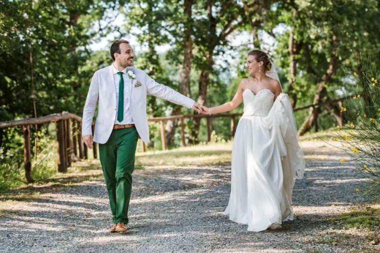Groom in green trousers leading his bride by the hand down a woodland path at Livernano Estate