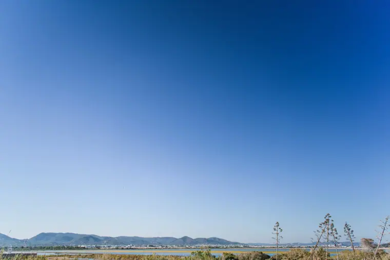 Clear blue sky over the salt flats and distant hills of Ibiza