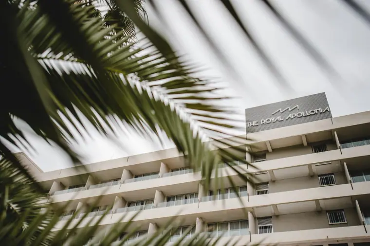 Royal Apollonia hotel facade and sign framed by palm fronds, Limassol