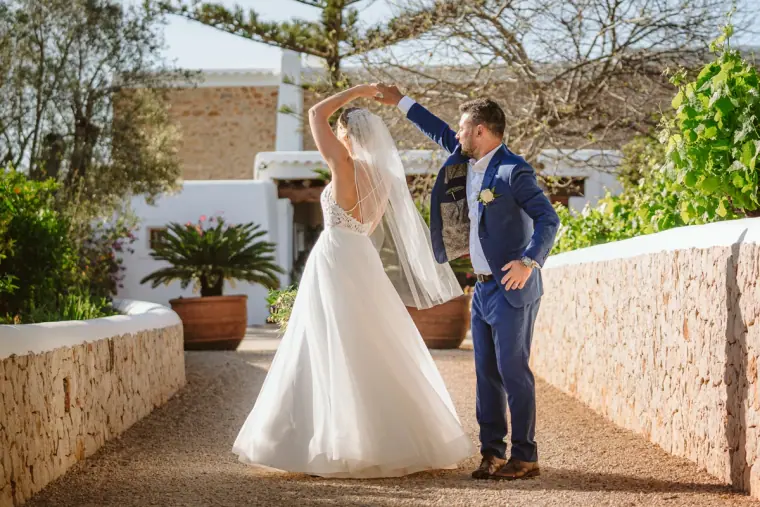 Iain twirling Sophie on a stone-walled path in front of the whitewashed farmhouse