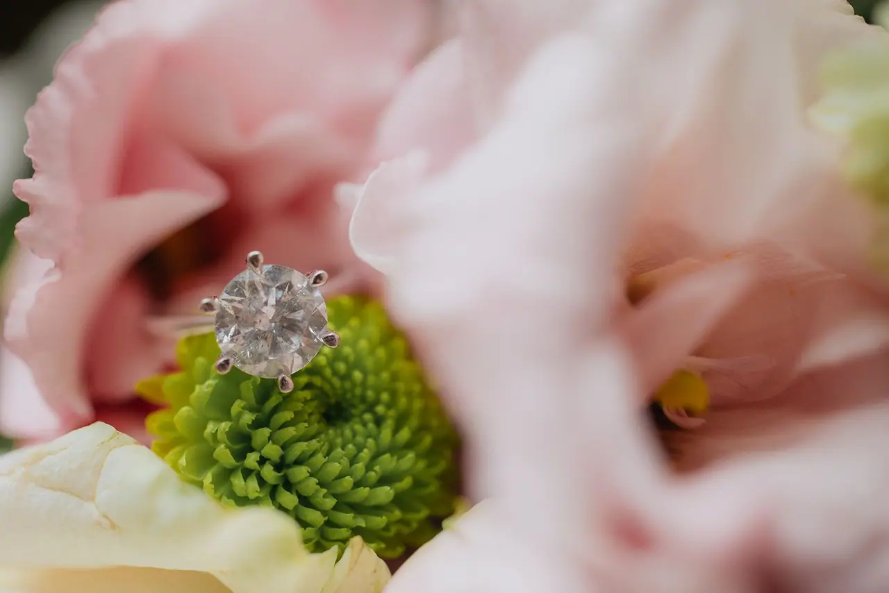 Engagement ring resting in the petals of a pink flower