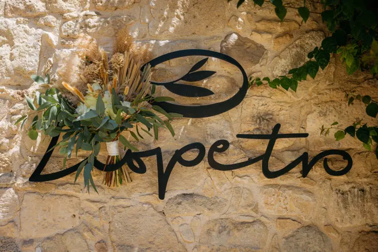 Liopetro sign on a stone wall decorated with dried flowers and pampas grass, Kouklia