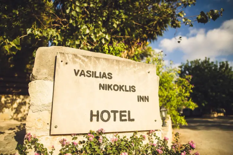 Stone Vasilias Nikoklis Inn Hotel sign surrounded by flowers