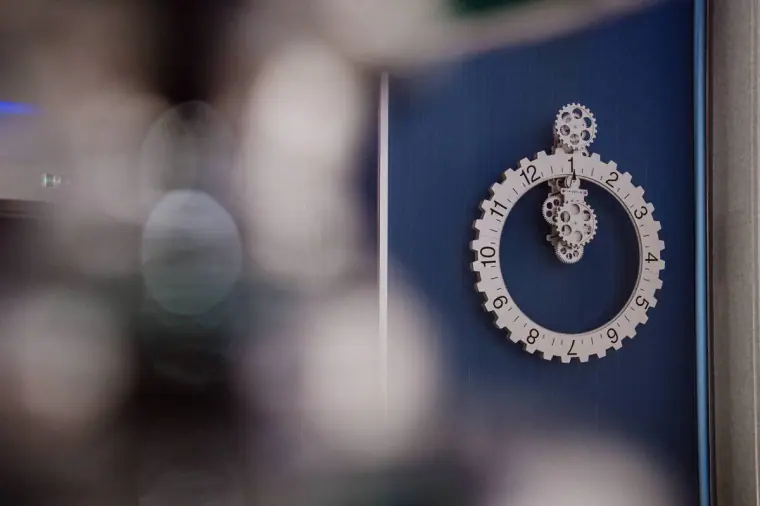 Ornate silver clock face on a navy wall, softly framed by blurred decor