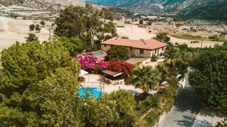 Aerial view of the inn's red roofs, pool and bougainvillea in the Paphos countryside