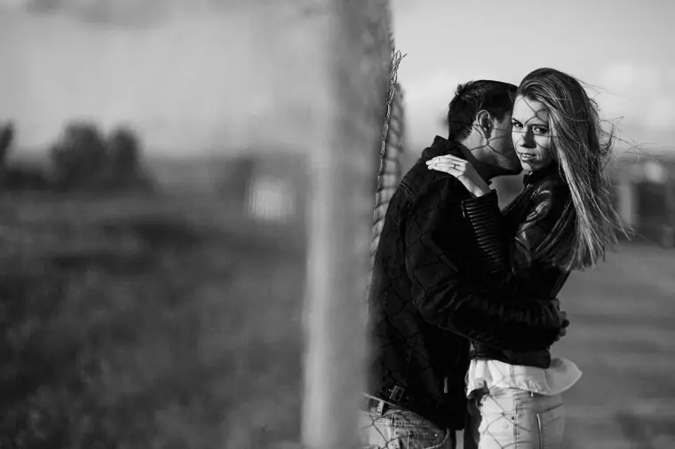 Black-and-white photo of Joanna and Andrew embracing beside a pole