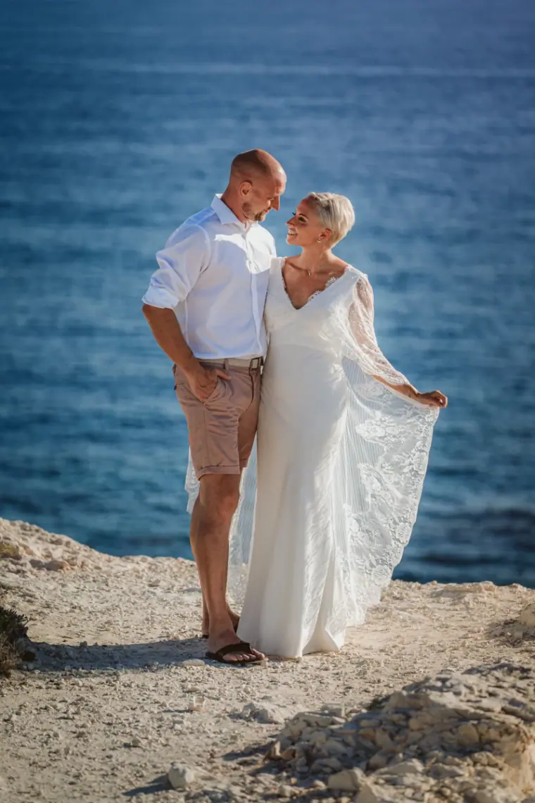 Alana and Luke standing on white rocks above the deep blue sea near Paphos