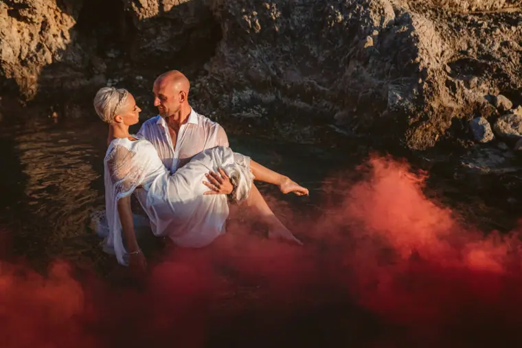 Luke carrying Alana through the water amid red smoke, Paphos