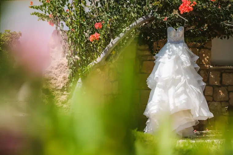 Ruffled wedding dress hanging from a bougainvillea tree in the garden at Coral Beach Hotel, Paphos