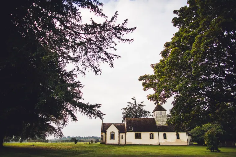 Small white church framed by trees across the lawns at Wasing Park