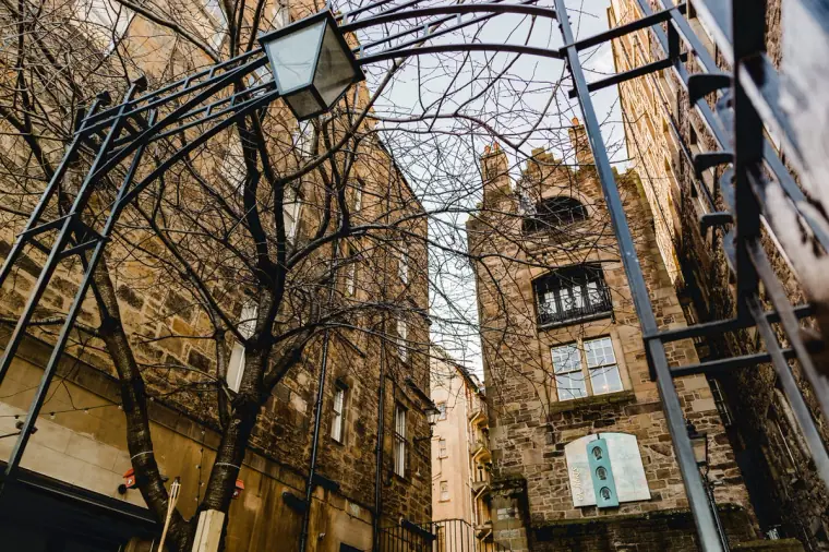 Ornate iron archway and lamp leading to a turreted stone building in Edinburgh's Old Town