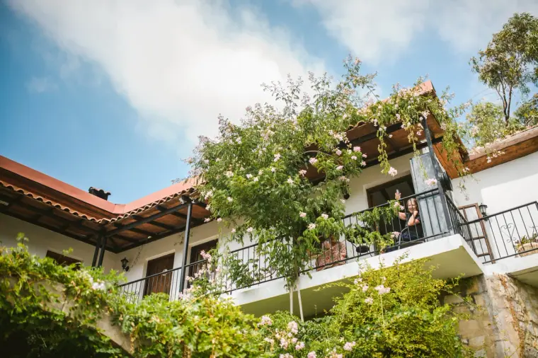 Vine-covered balconies of Vasilias Nikoklis Inn under a bright blue sky