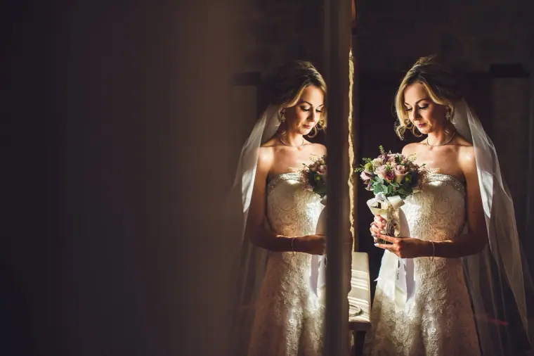 Bride holding her bouquet, reflected in a mirror beside a doorway at Liopetro