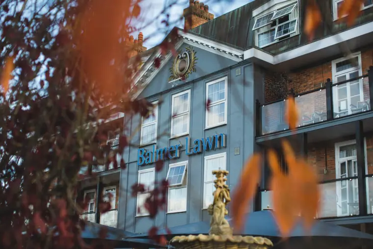 Balmer Lawn Hotel facade and fountain glimpsed through autumn leaves, New Forest
