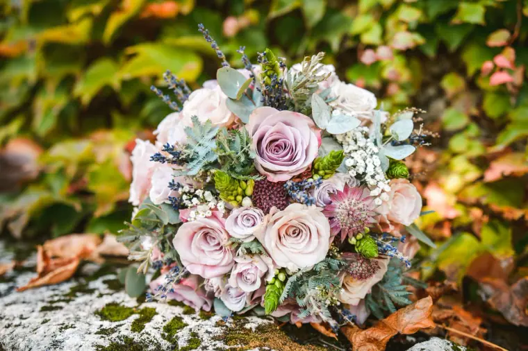 Bouquet of lilac roses, thistles and eucalyptus resting on autumn ivy at Chateau Rigaud, France