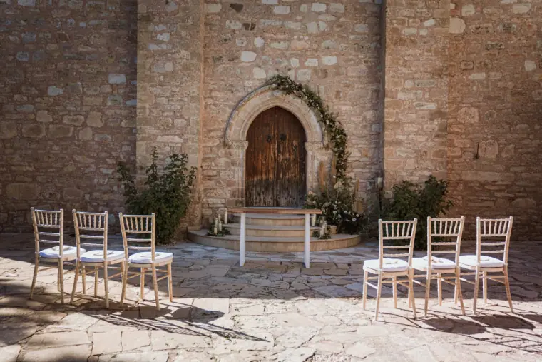 Stone chapel doorway with an ivy garland and white chairs set for the ceremony