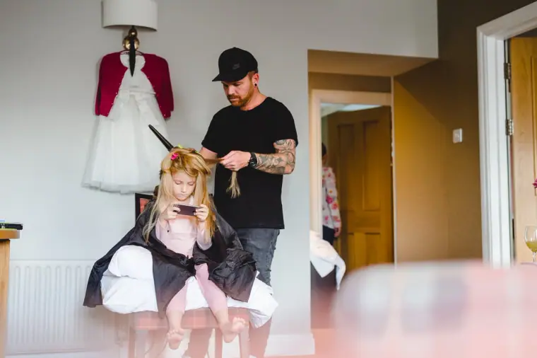 Young bridesmaid having her hair styled by a hairdresser while getting ready