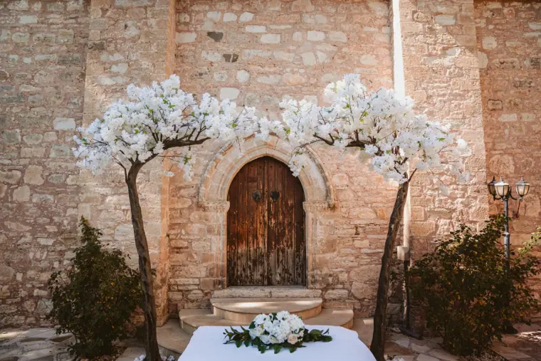 Ceremony table framed by white blossom trees in front of the chapel's arched door