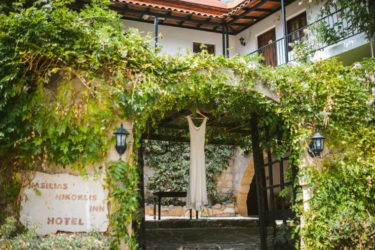 Wedding dress hanging in the ivy-covered stone archway of Vasilias Nikoklis Inn