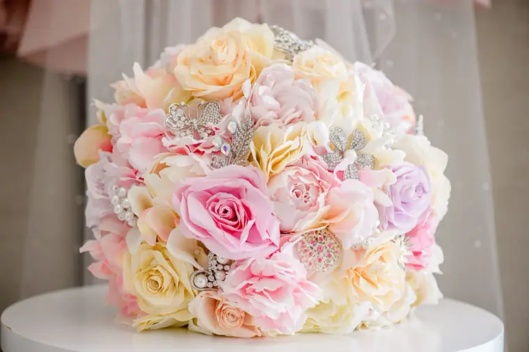 Pastel bouquet of pink, peach and cream roses with sparkling brooches