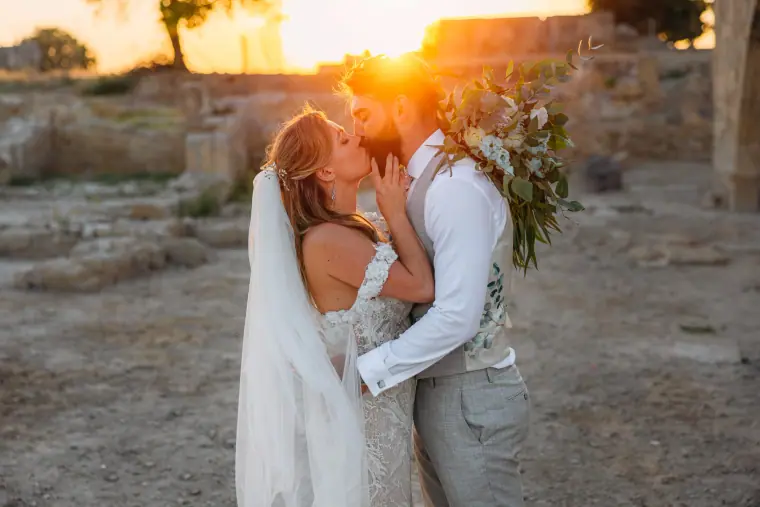 Sunset kiss for a bride and groom among ancient stone ruins at Liopetro, Kouklia