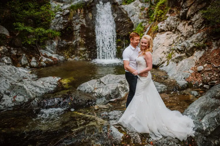 Bride and groom embracing beside a waterfall in the Troodos Mountains
