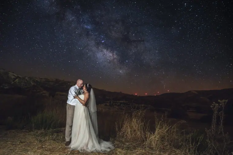 Bride and groom beneath the Milky Way in a starry night sky