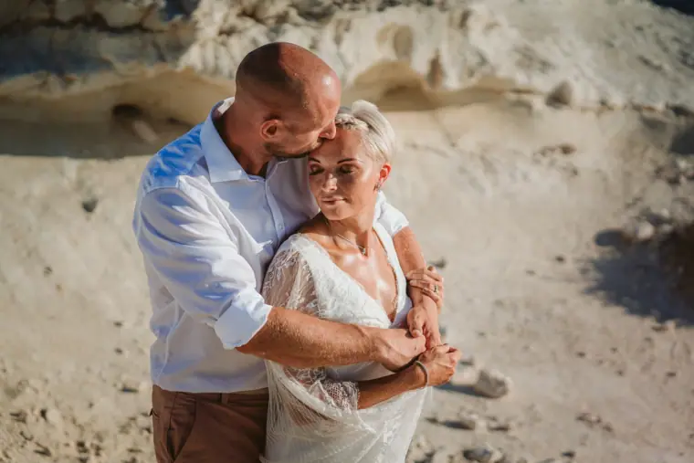 Luke hugging Alana from behind on sunlit limestone rocks