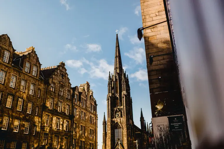 Gothic church spire rising between sunlit tenement buildings in Edinburgh