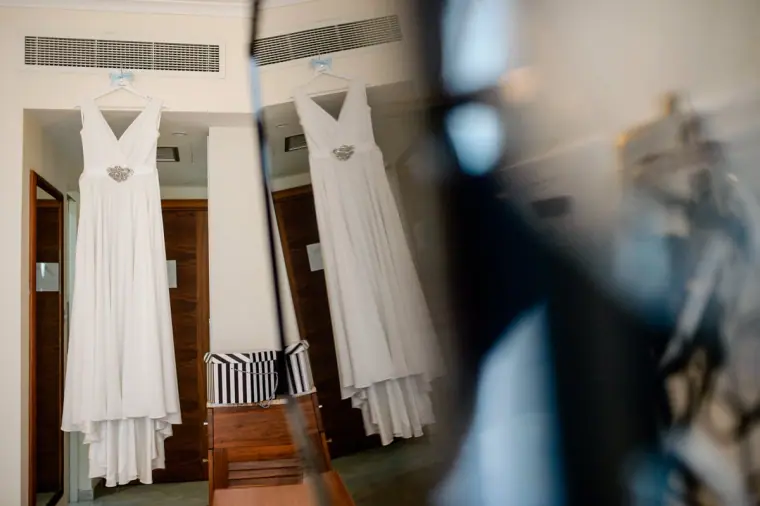 Wedding dress and a bridesmaid dress hanging in a hotel room doorway