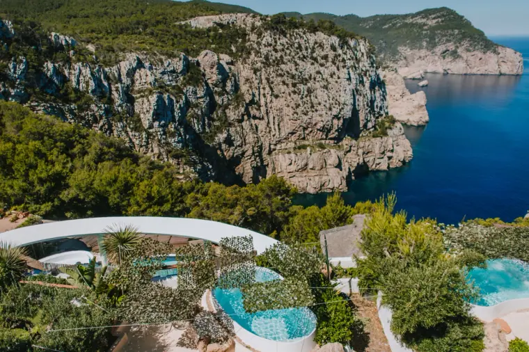 Dramatic sea cliffs above a villa with a curved infinity pool, Ibiza