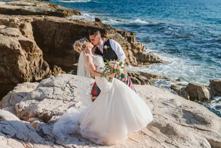 Lyndsay and Fraser embracing on white rocks by the sea at Cap St Georges, Paphos