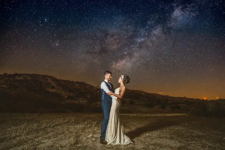 Bride and groom embracing under a starry sky with the Milky Way overhead