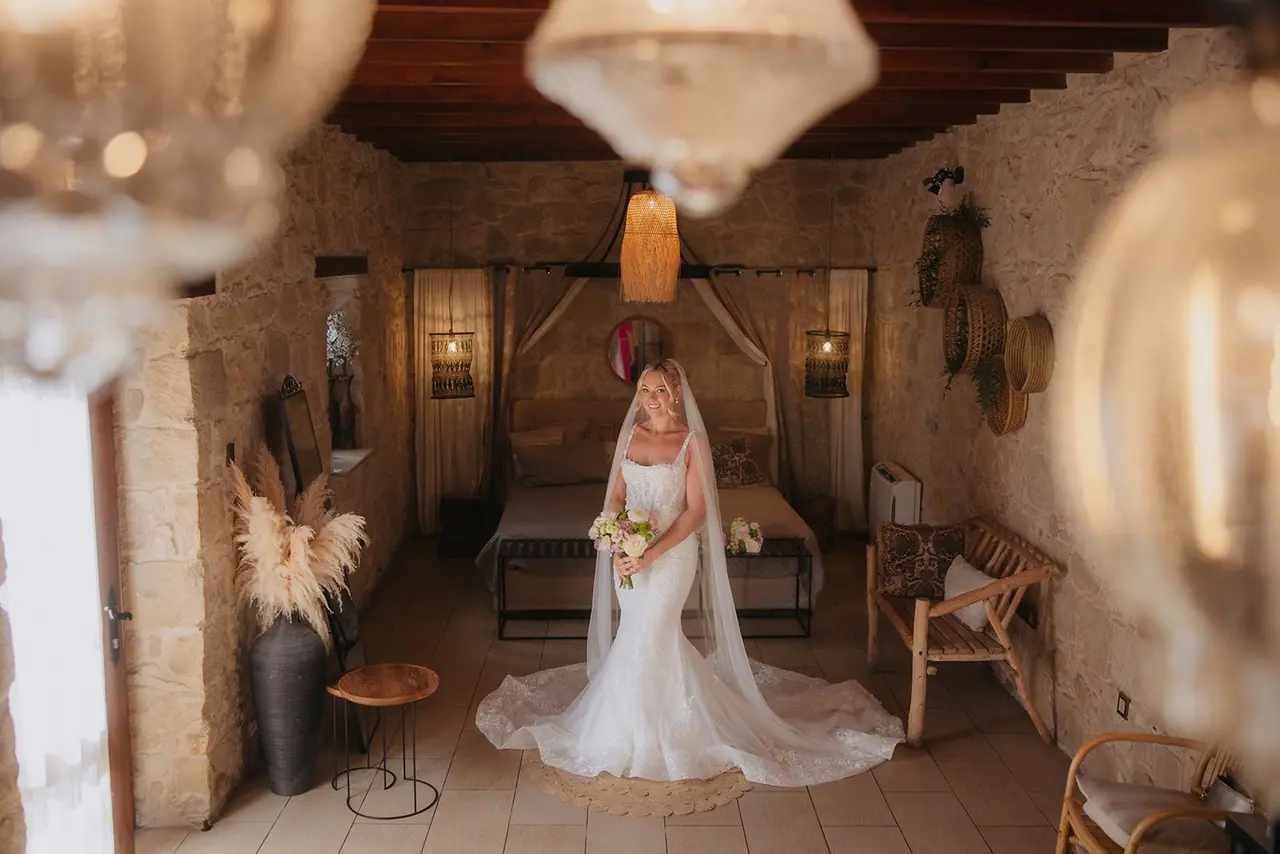 Zoe in her wedding dress and veil beneath a glass lantern in Liopetro's stone bridal suite