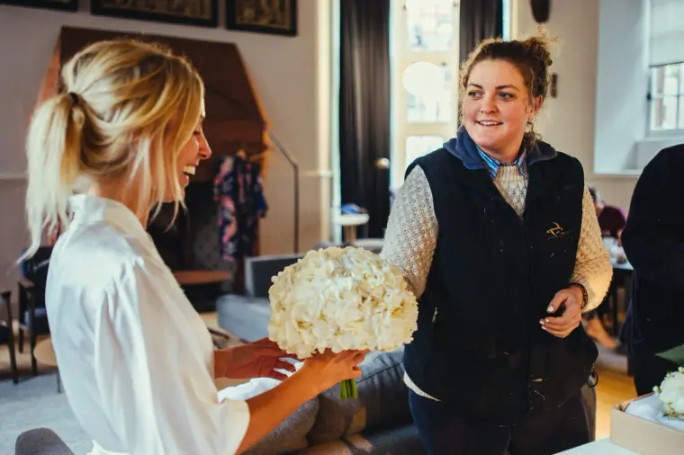 Bridesmaid receiving a bouquet of white roses from the florist